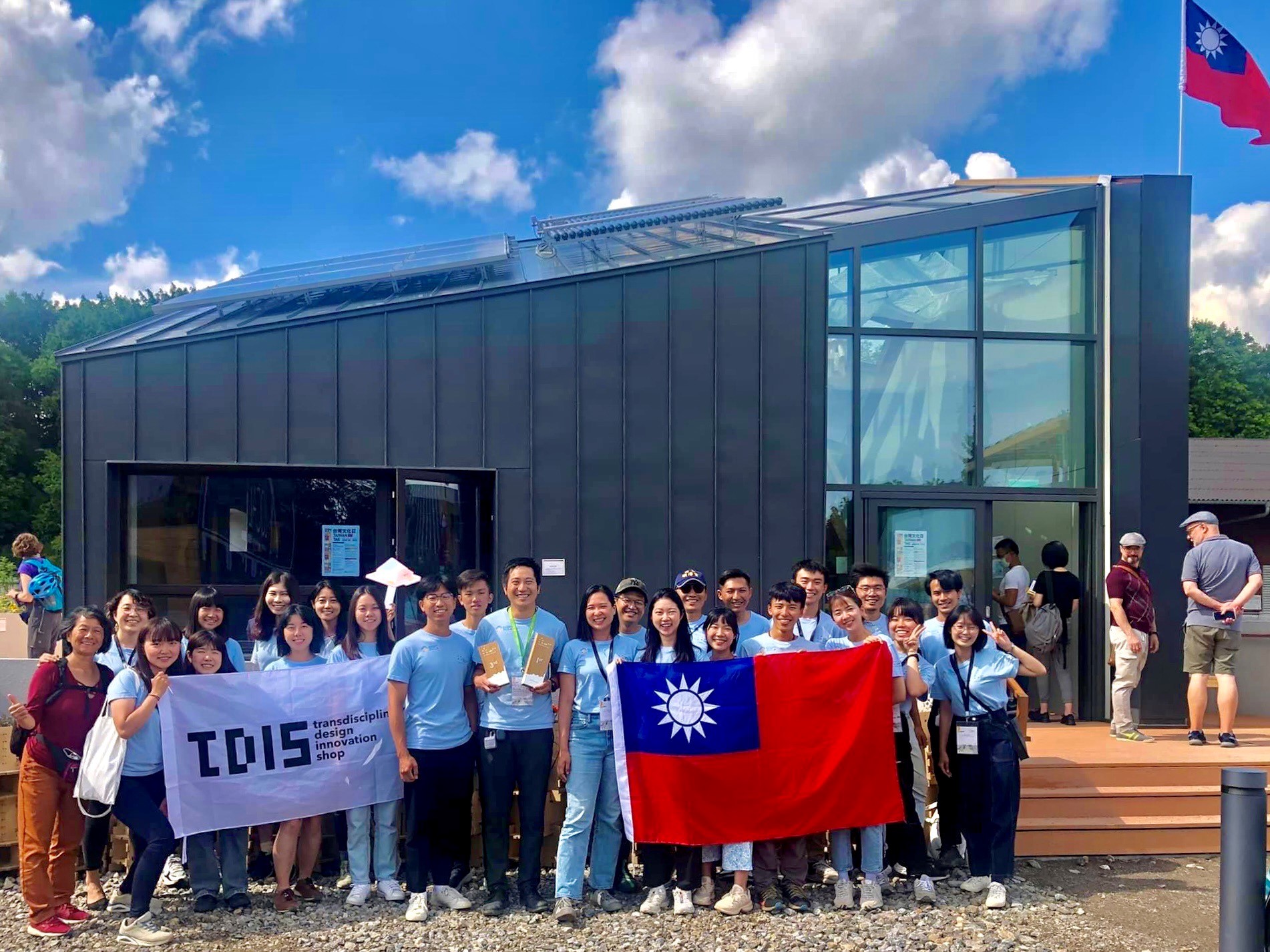 得獎後，台灣隊與「台灣厝」與千里迢迢帶去的國旗與研究中心大旗合影